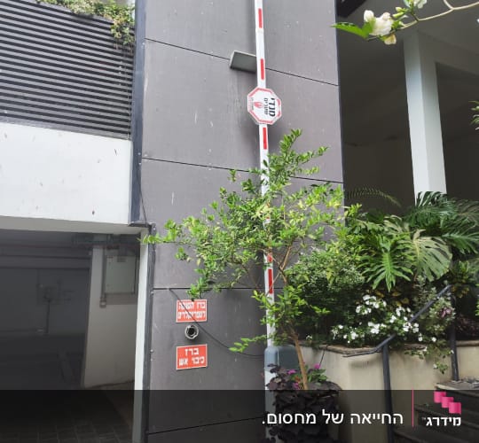 שער חשמלי בכניסה לחניון עם צמחייה מסביב